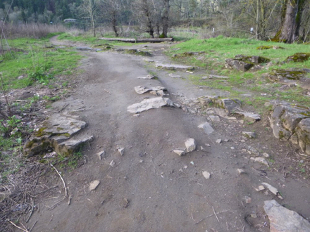 Compacted gravel trail transitions to hard-packed soil with many rock obstacles